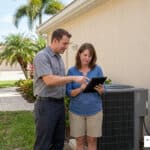 HVAC technician and homeowner reviewing AC repair vs replacement options outside an Ellenton Florida home