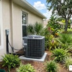 well-maintained outdoor AC unit in Palmetto, FL with lush Florida landscaping and clear blue sky